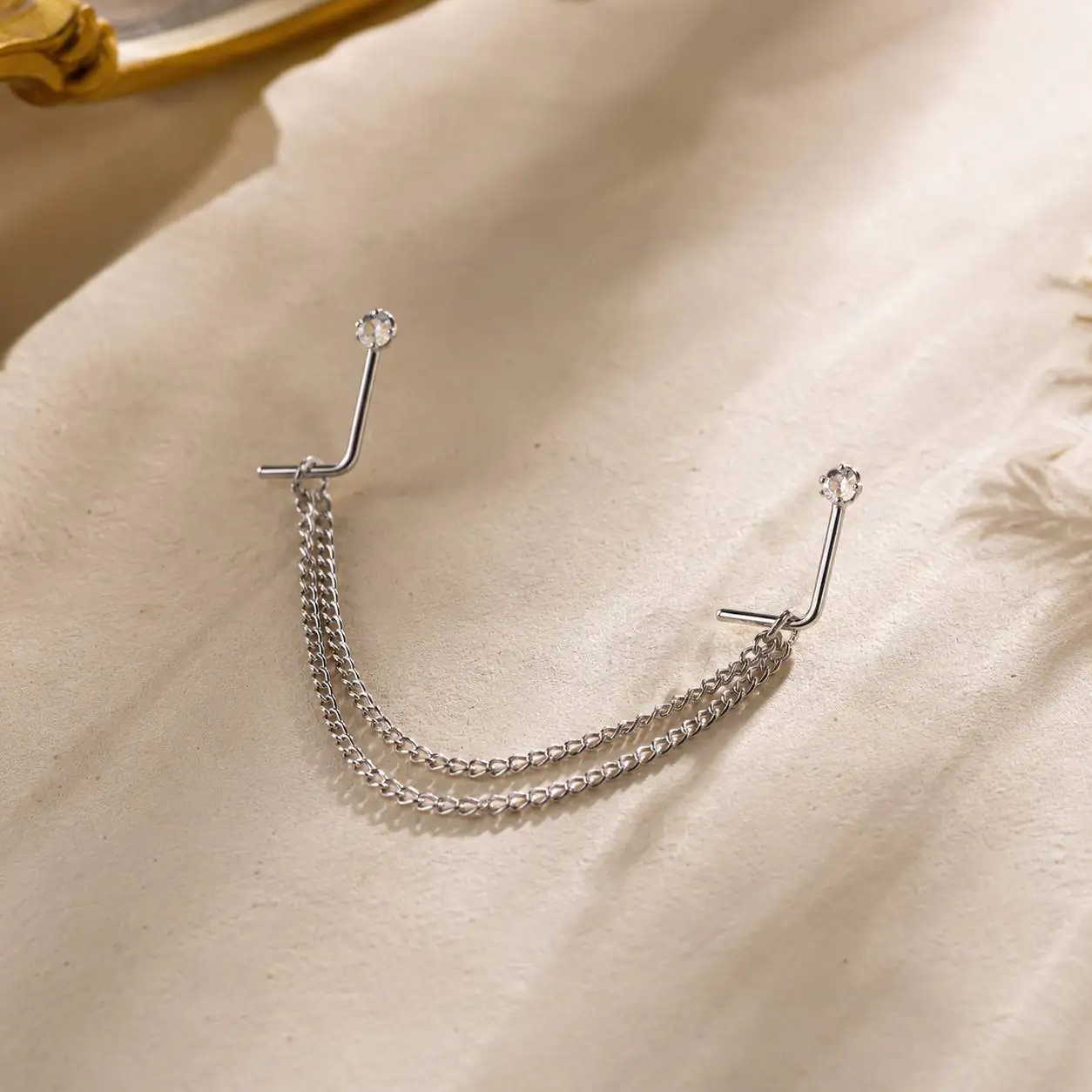 crystal-gem-nose-piercing-jewelry نمای نزدیک پیرسینگ بینی نقرهای با طراحی زنجیری و نگین شفاف