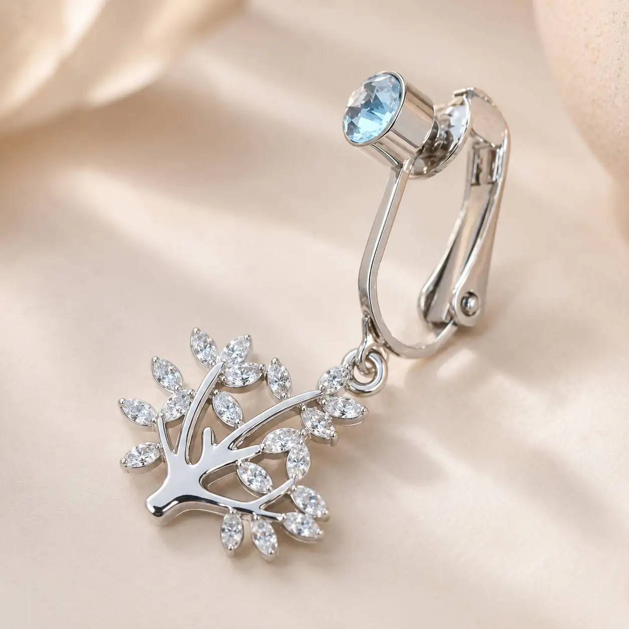 crystal-tree-navel-piercing-silver.jpg` پیرسینگ فیک ناف نقرهای با نگین آبی و آویز درخت کریستالی روی پس زمینه روشن