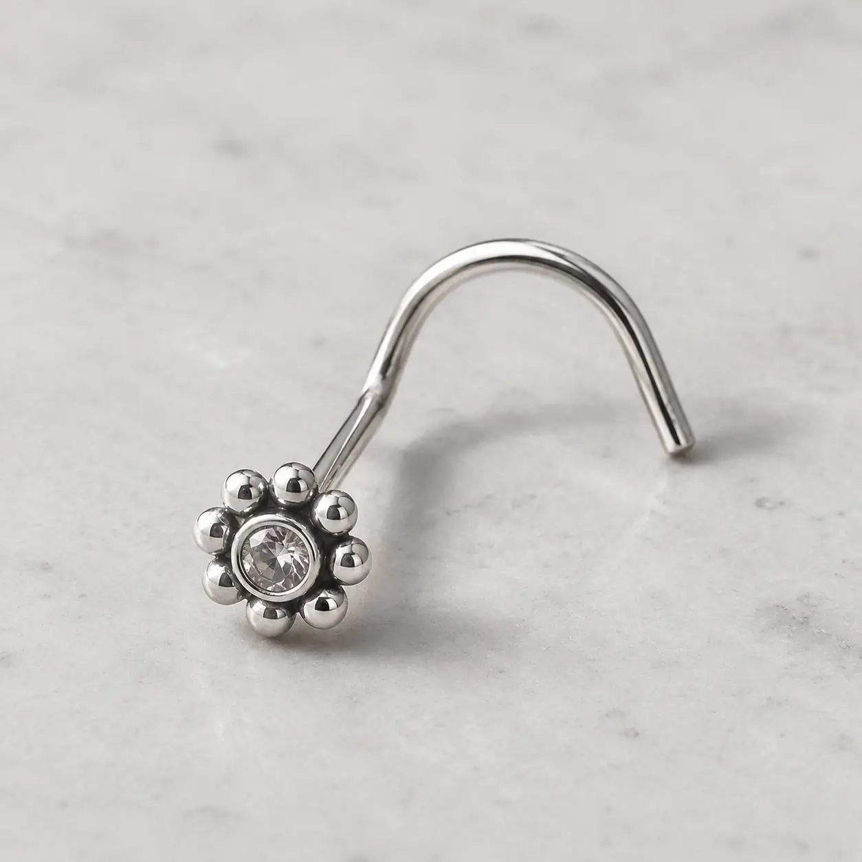 curved-flower-gem-nose-piercing-side-view تصویر ماکرو پیرسینگ بینی گلدانهای نقرهای روی پسزمینه روشن