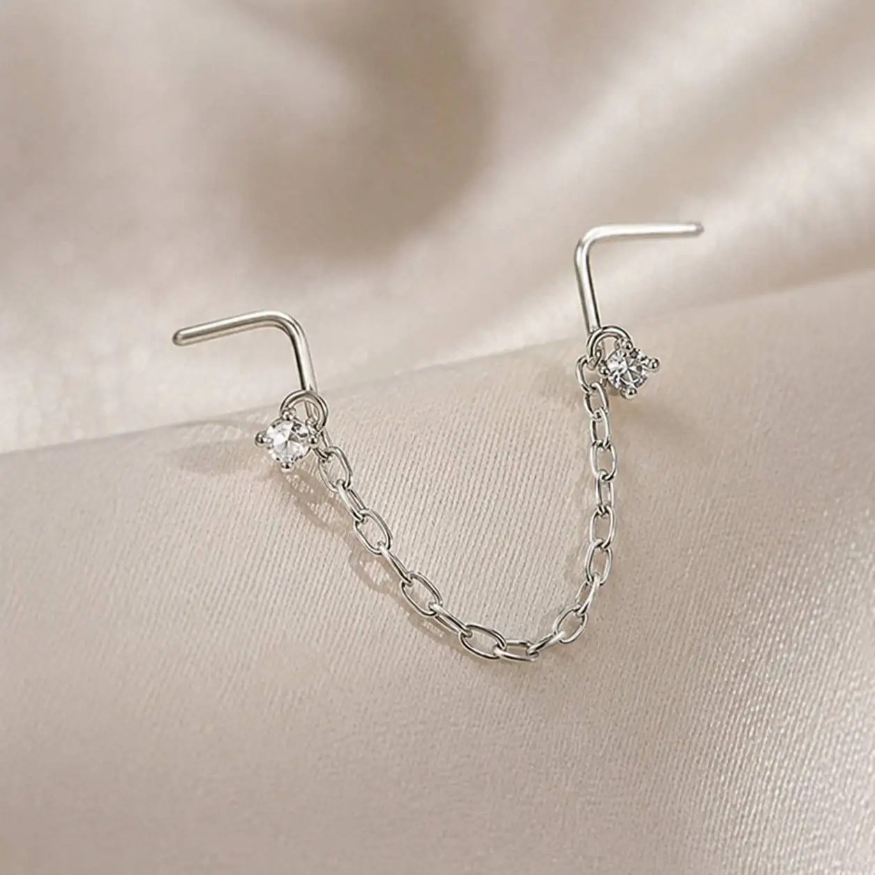 gemstone-nose-chain-piercing-closeup.jpg نمای نزدیک پیرسینگ بینی مدل زنجیری با نگین شفاف و پایه فلزی نقرهای