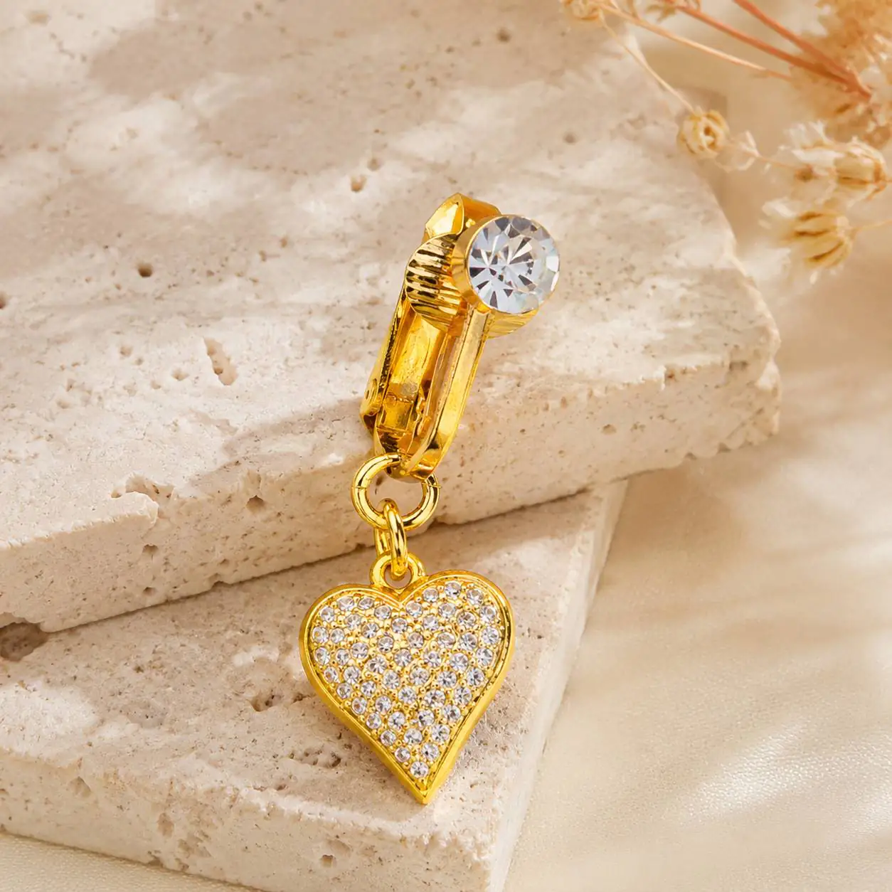 gold-heart-navel-piercing-crystal-detail پیرسینگ فیک ناف طلایی قلبی با نگین کریستالی روی پس زمینه سنگی روشن