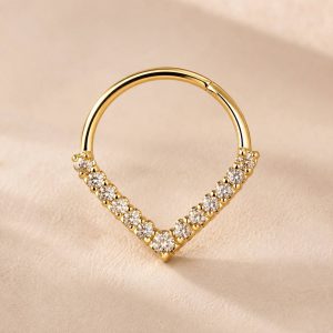 پیرسینگ سپتوم طلایی مدل V با ردیف نگینهای ریز و شفاف روی زمینه روشن