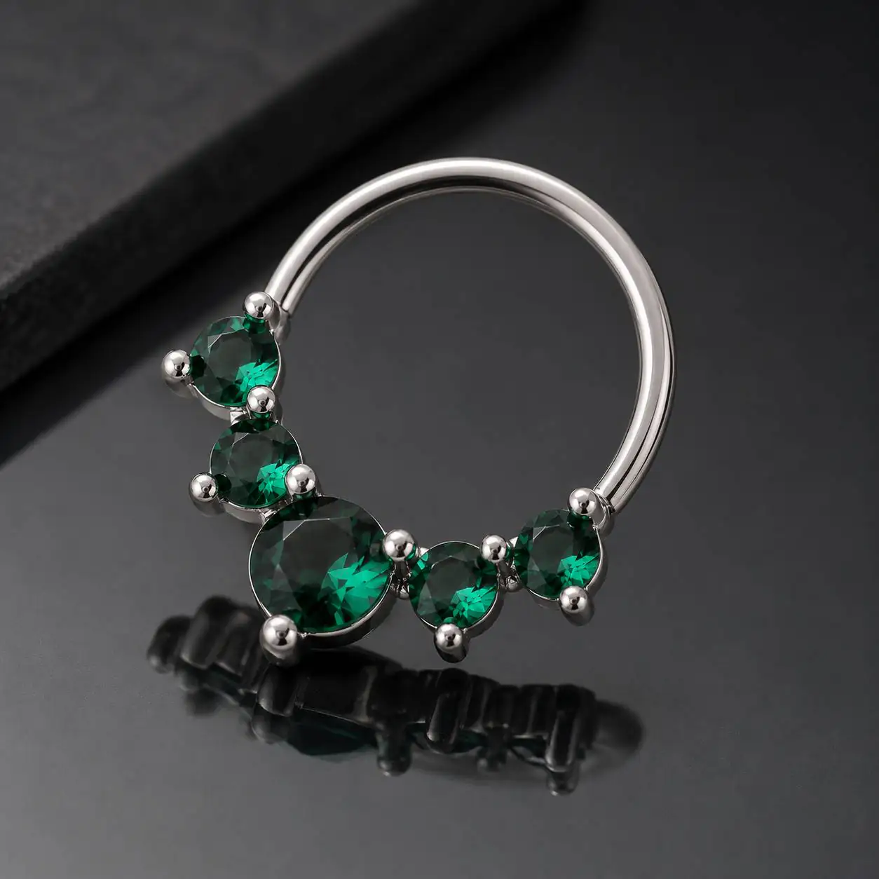green-gem-septum-piercing-closeup تصویر نزدیک از پیرسینگ سپتوم نگیندار سبز با حلقه نقرهای براق
