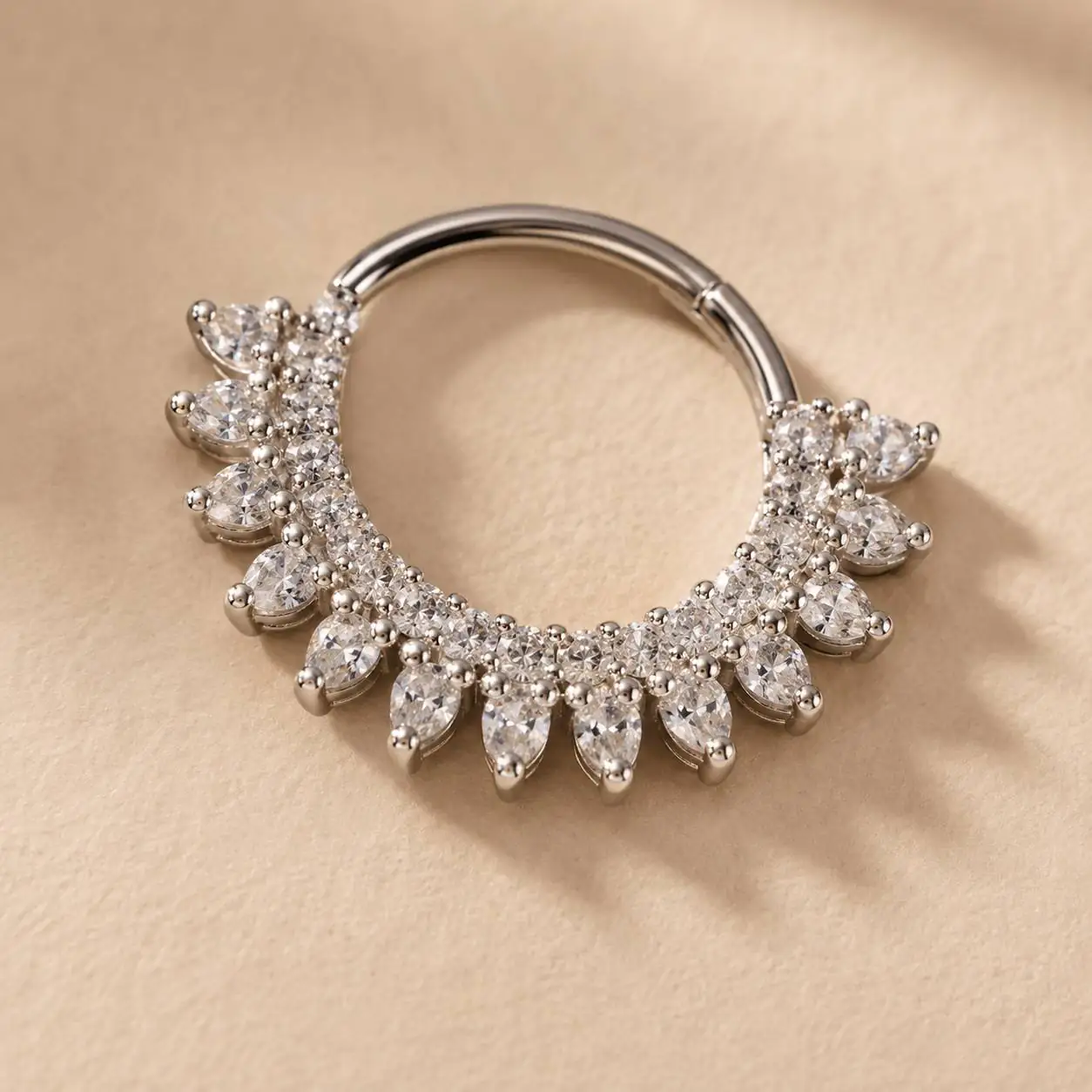 marquise-gem-septum-clicker-on-ivory-bg نمای نزدیک پیرسینگ سپتوم کلیکر با نگینهای مارکیز و بدنه نقرهای براق