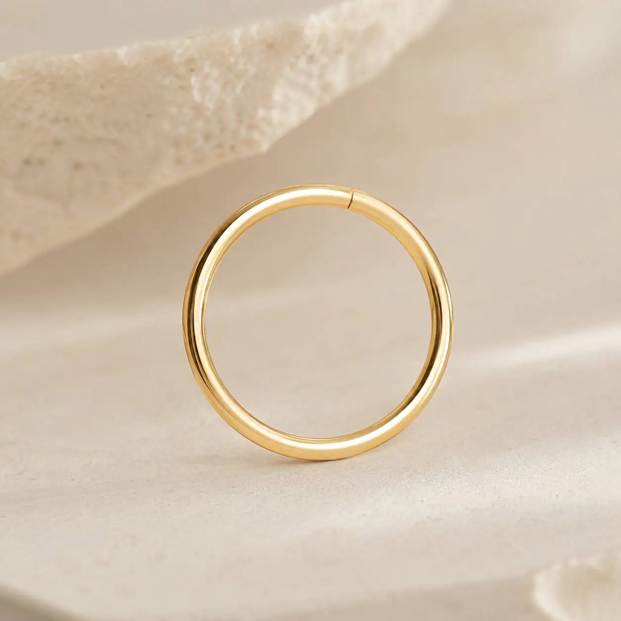 minimal-gold-septum-ring-product نمای نزدیک از رینگ سپتوم طلایی براق با فرم گرد و ظریف