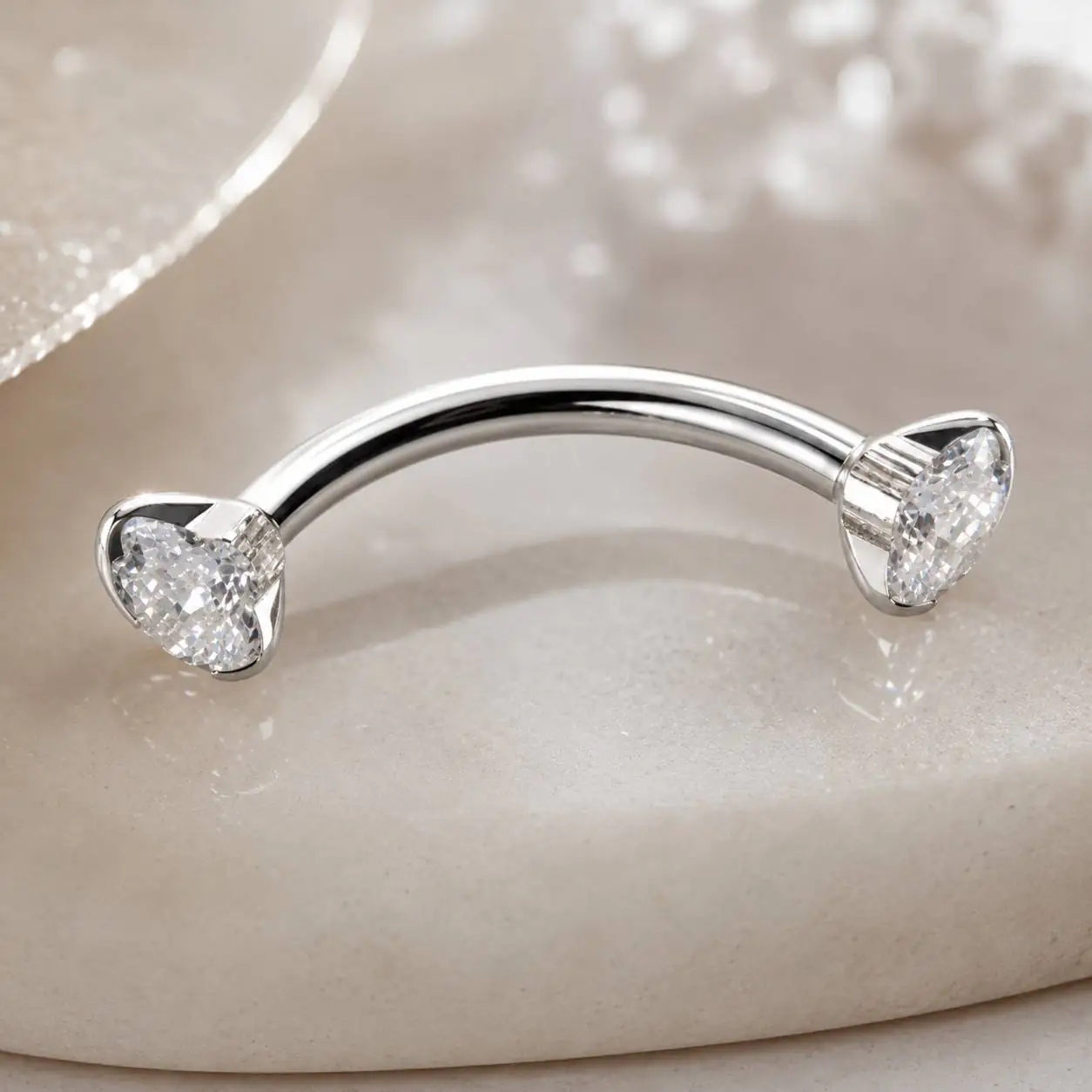 silver-clear-gem-eyebrow-piercing-closeup.jpg نمای نزدیک پیرسینگ ابرو هلالی با نگینهای شفاف و درخشان