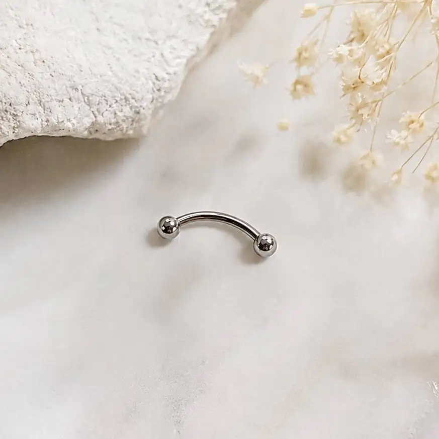 silver-curved-eyebrow-piercing-minimal-background.jpg پیرسینگ ابرو میله خمیده با دو گوی براق روی پسزمینه روشن