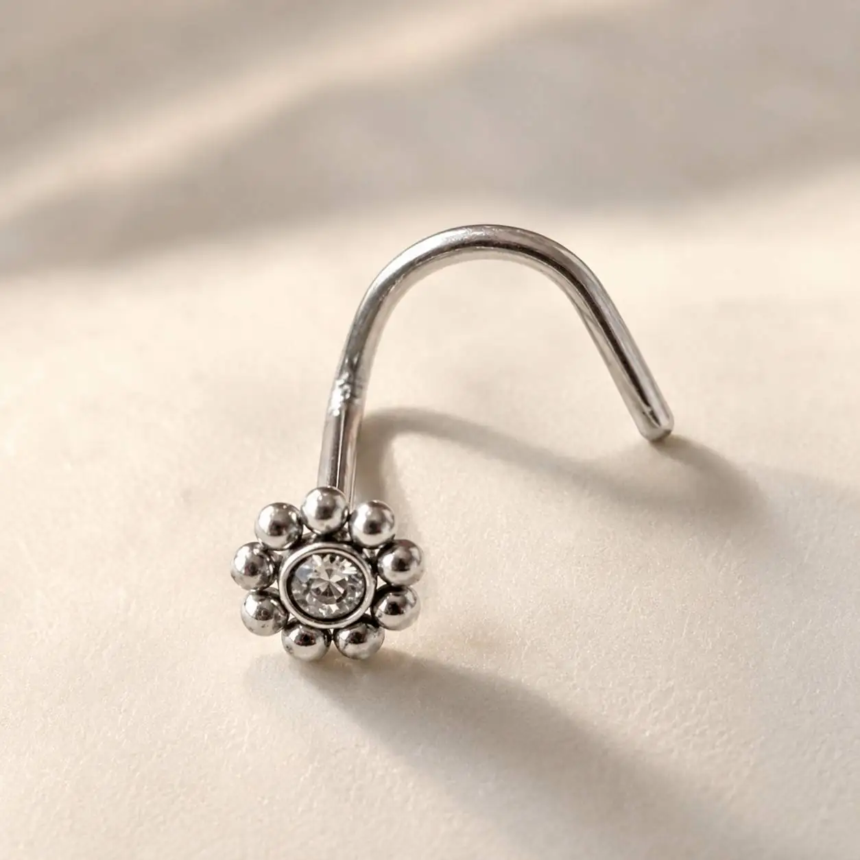 silver-daisy-nose-stud-macro-view نمای جانبی پیرسینگ بینی طرح گل با نگین شفاف و میله قلابی نقرهای