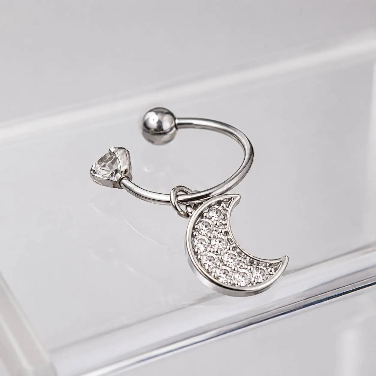 silver-triangle-gem-moon-nose-ring-detail نمای نزدیک پیرسینگ بینی نقرهای با نگین شفاف و آویز ماه درخشان