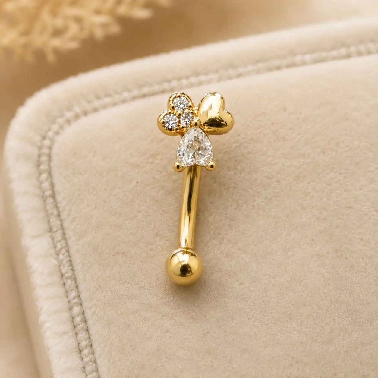 teardrop-gem-eyebrow-piercing-velvet پیرسینگ ابرو نگیندار طلایی روی زمینه مخملی کرم