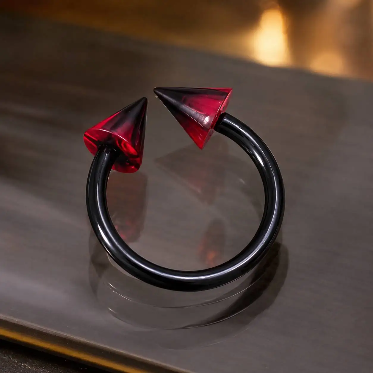 black-smiley-piercing-red-spikes-reflective-surface نمای زاویهدار پیرسینگ اسمایل سیلیکونی مشکی و قرمز روی سطح بازتابی