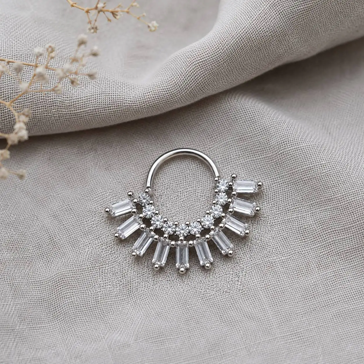 close-up-silver-septum-piercing-gray-velvet نمای نزدیک پیرسینگ سپتوم نقرهای با نگینهای شفاف روی پارچه مخمل خاکستری
