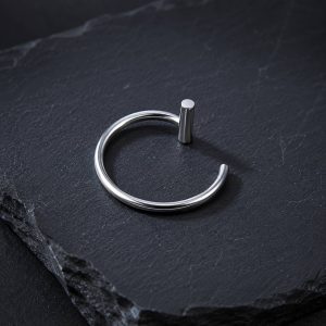پیرسینگ فیک لب حلقه‌ای نقره‌ای میله‌دار روی پس‌زمینه سنگی تیره