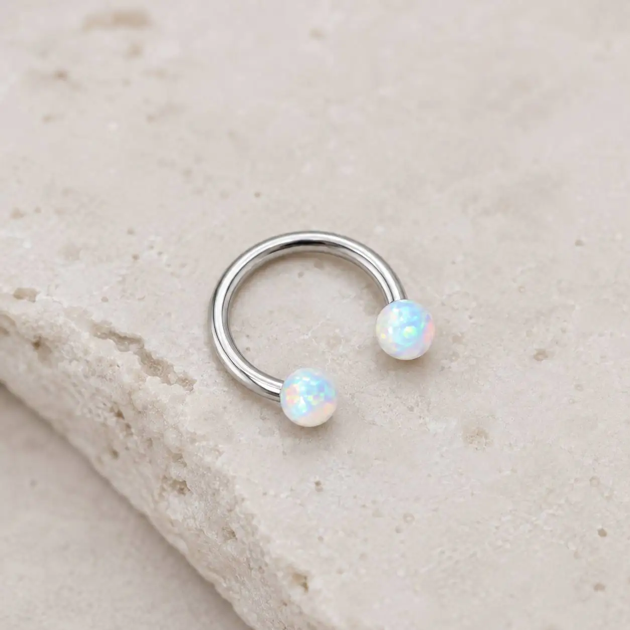 silver-opal-smiley-piercing-marble-closeup نمای نزدیک پیرسینگ اسمایل اپال سفید روی سطح مرمری روشن