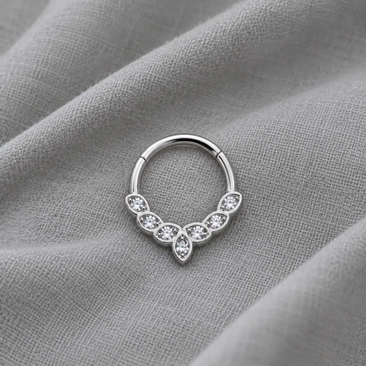 silver-septum-piercing-gray-cotton نمای متوسط پیرسینگ سپتوم نقرهای با نگینهای شفاف روی پارچه نخی خاکستری