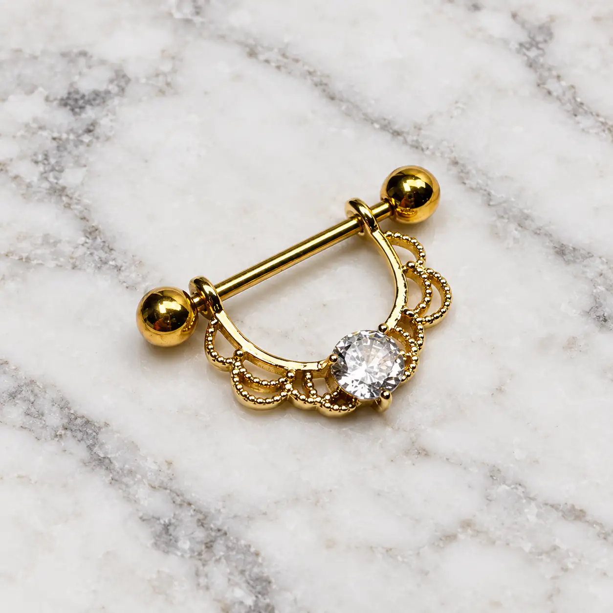elegant-gold-nipple-piercing-marble پیرسینگ نیپل طلایی ظریف روی پس زمینه سنگ مرمر سفید