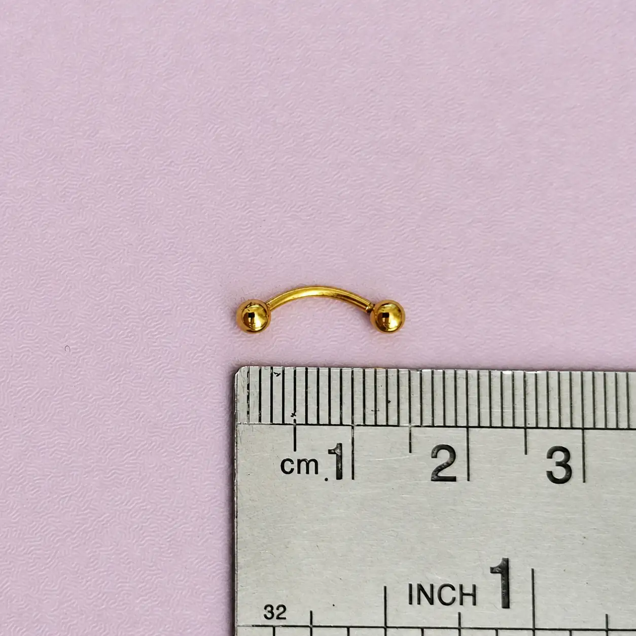 gold-curved-eyebrow-barbell-with-rule پیرسینگ ابرو طلایی مدل میله خمیده با دو گوی کنار خطکش