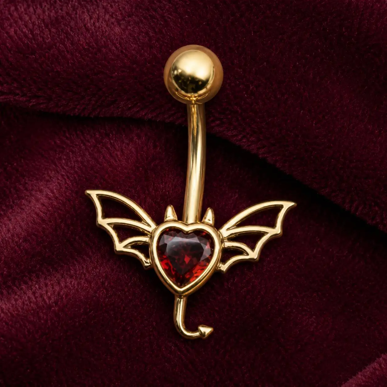 red-heart-bat-wing-navel-piercing-closeup پیرسینگ ناف طلایی طرح قلب قرمز با بال خفاشی از نمای نزدیک