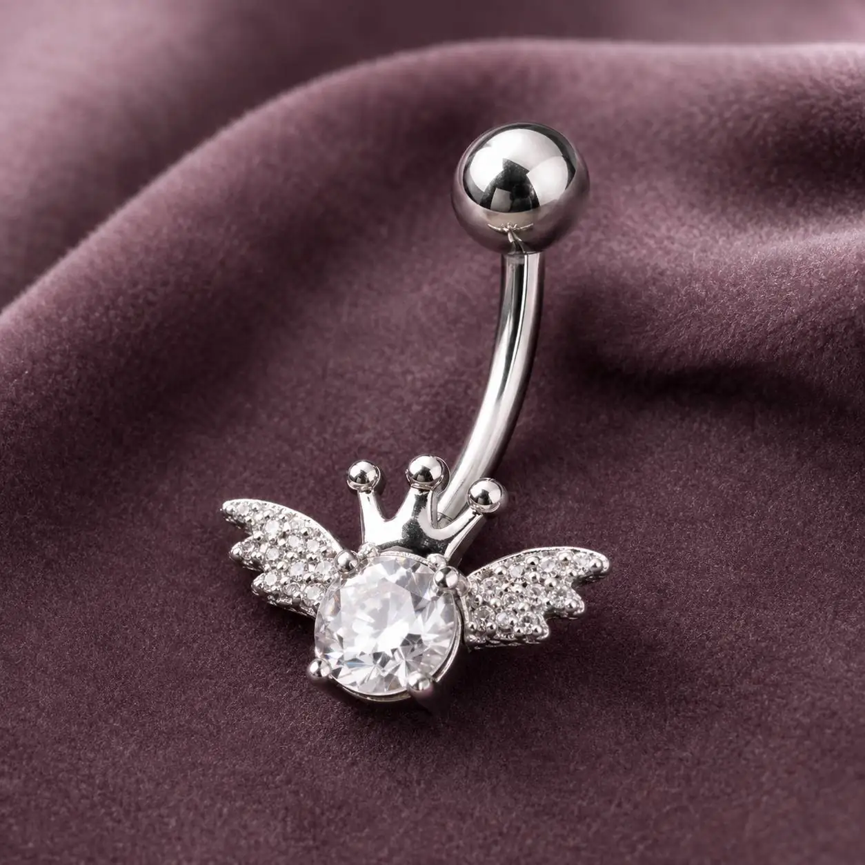 silver-crown-wing-navel-piercing-closeup پیرسینگ ناف نقرهای نگیندار طرح تاج و بال فرشته نمای نزدیک