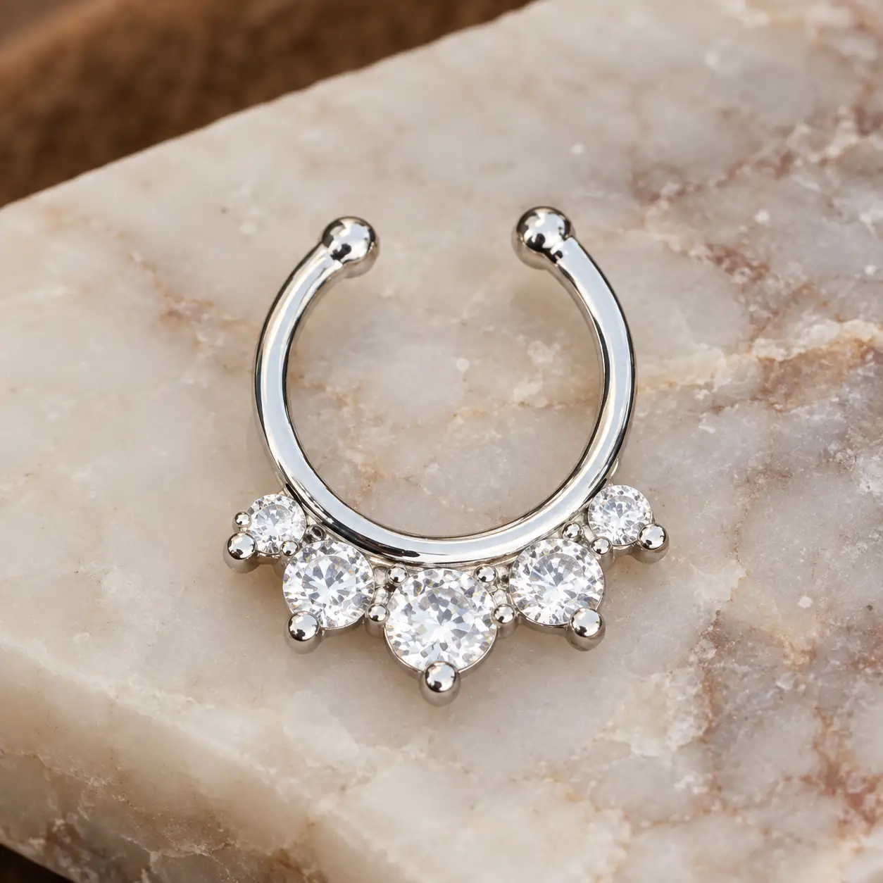 silver-faux-septum-crystal-jewelry-product پیرسینگ بینی فیک سپتوم نقرهای نگیندار روی پسزمینه سنگی
