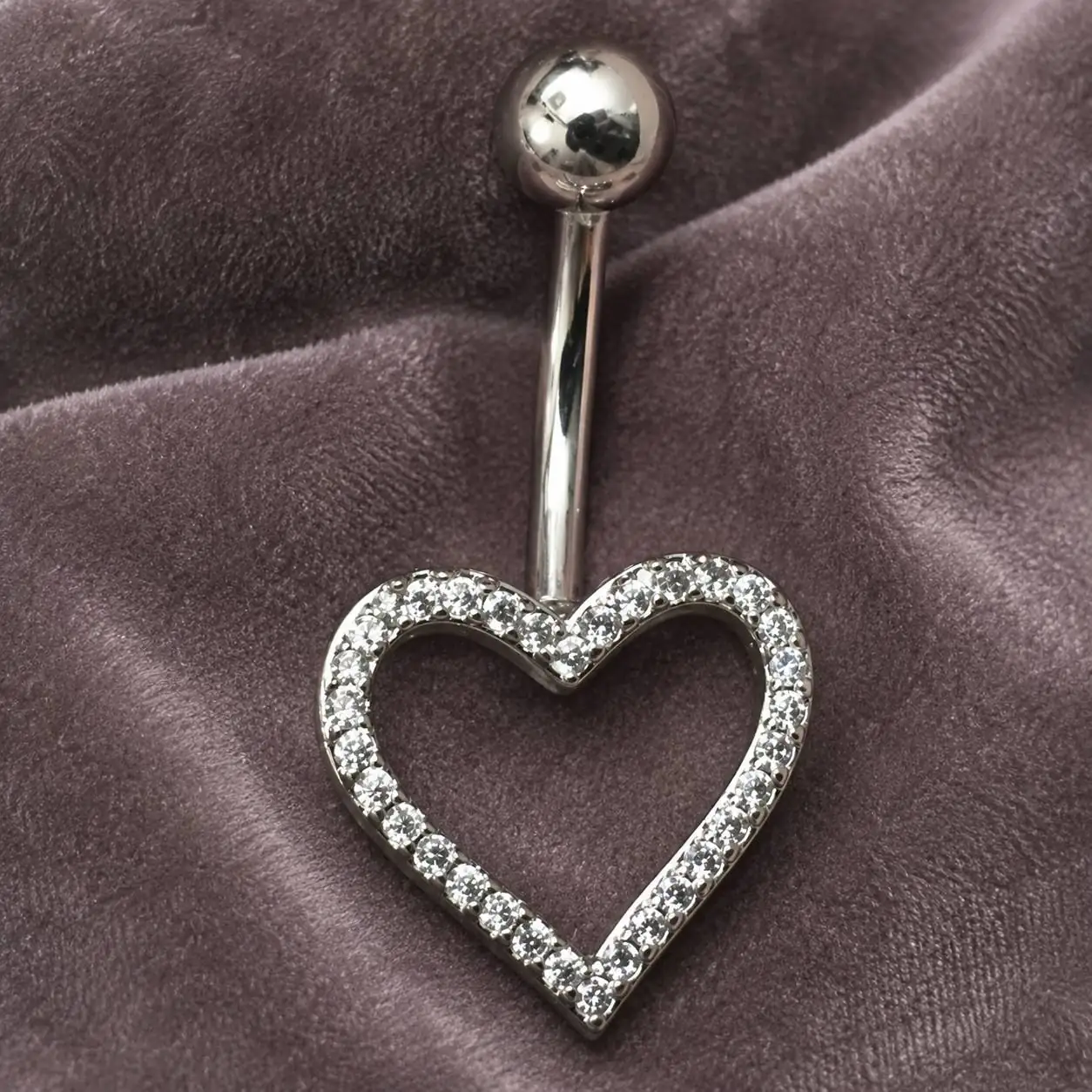 silver-open-heart-navel-piercing-close-up پیرسینگ ناف نقرهای طرح قلب توخالی با حاشیه نگین شفاف