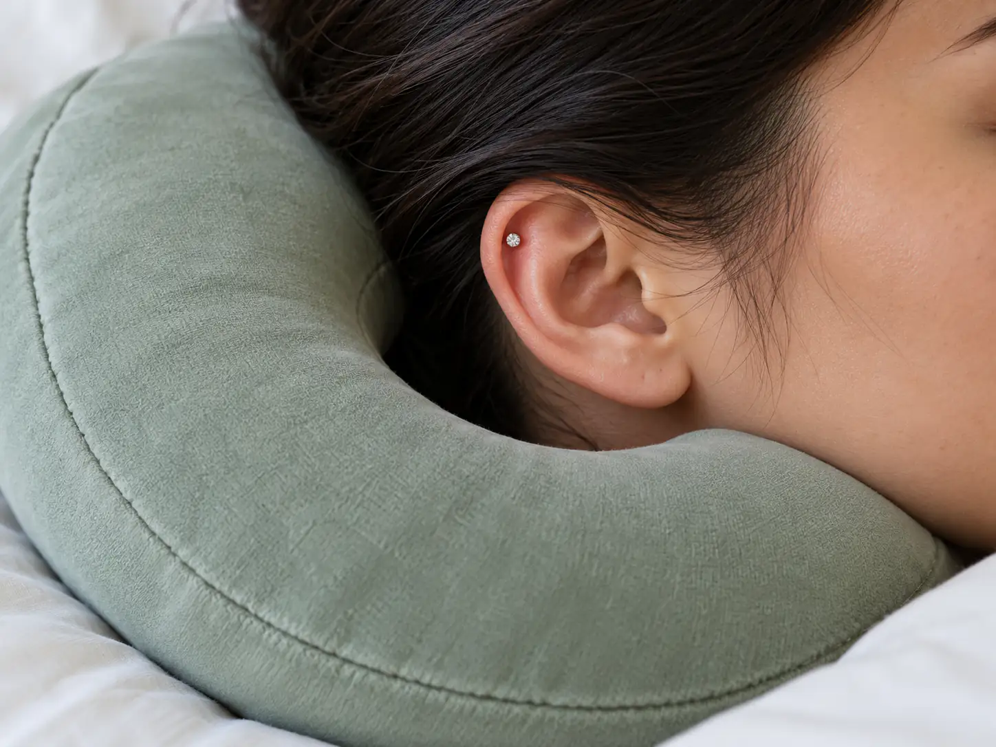 قرار گرفتن گوش دارای پیرسینگ در فضای خالی بالش بدون تماس زیور با پارچه